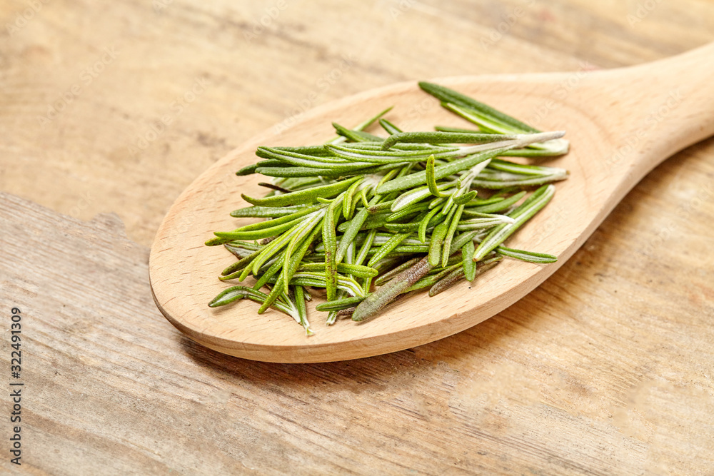 Wooden spoon with fresh rosemary on background. Close up. Wooden spoon with fresh rosemary on background. Close up.