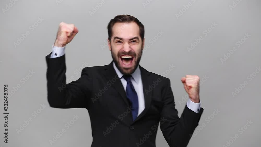 Successful young business man 20s in classic black suit shirt tie posing isolated on grey background studio. Achievement career wealth business concept Mock up copy space. Doing winner gesture say Yes Successful young business man 20s in classic black suit shirt tie posing isolated on grey background studio. Achievement career wealth business concept Mock up copy space. Doing winner gesture say Yes
