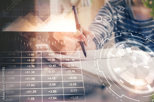 Financial forex graph drawn over hands taking notes background. Concept of research. Double exposure