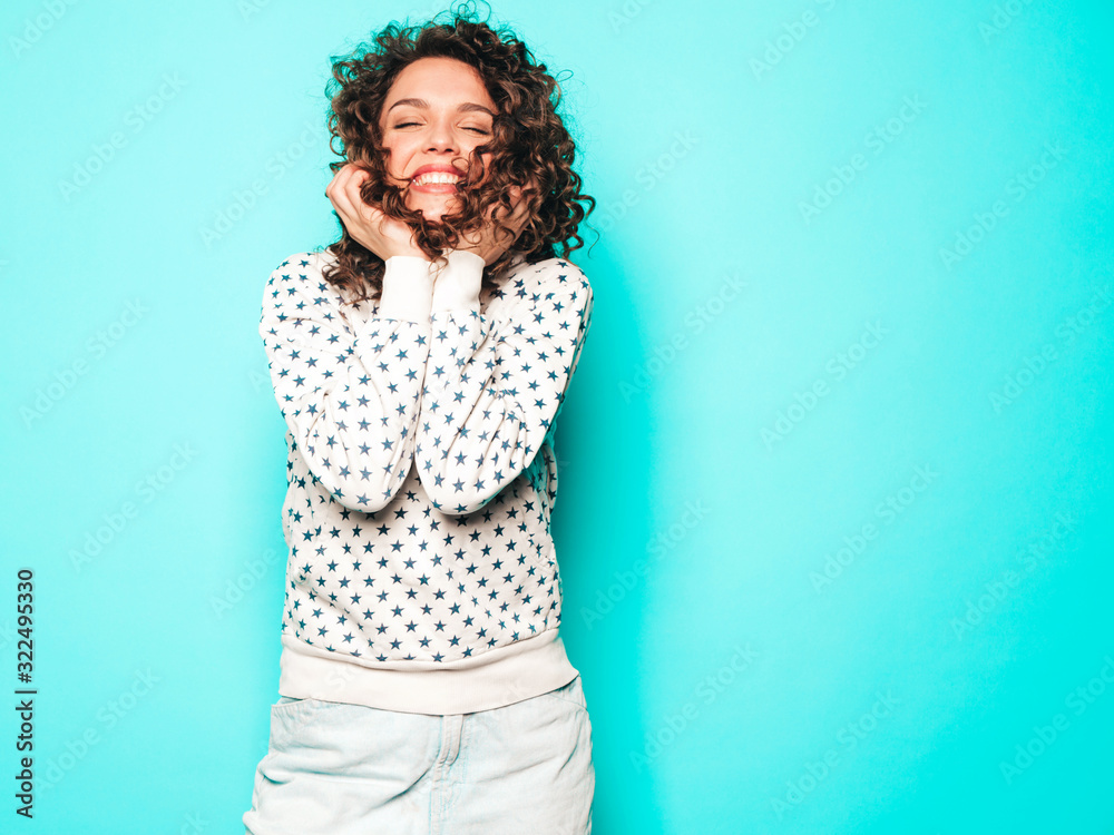Portrait of beautiful smiling model with afro curls hairstyle dressed in summer hipster clothes.Sexy carefree girl posing near blue wall.Trendy funny and positive woman in white hoodie Portrait of beautiful smiling model with afro curls hairstyle dressed in summer hipster clothes.Sexy carefree girl posing near blue wall.Trendy funny and positive woman in white hoodie