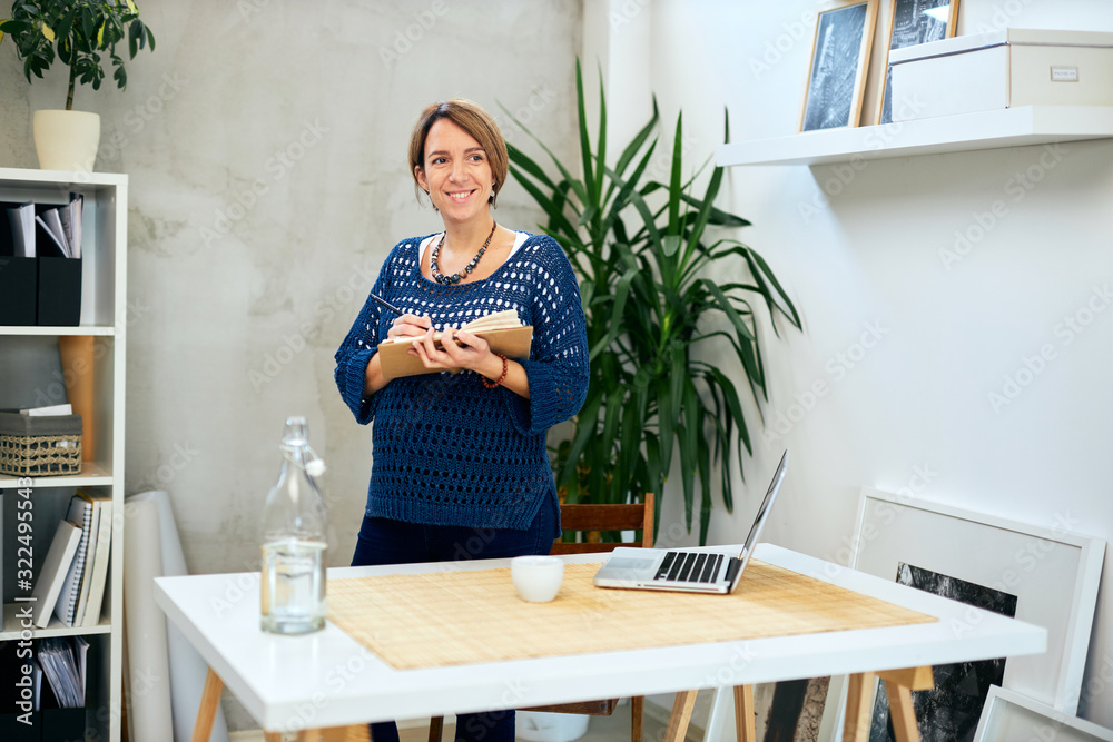 Attractive pregnant businesswoman taking notes in modern office interior.