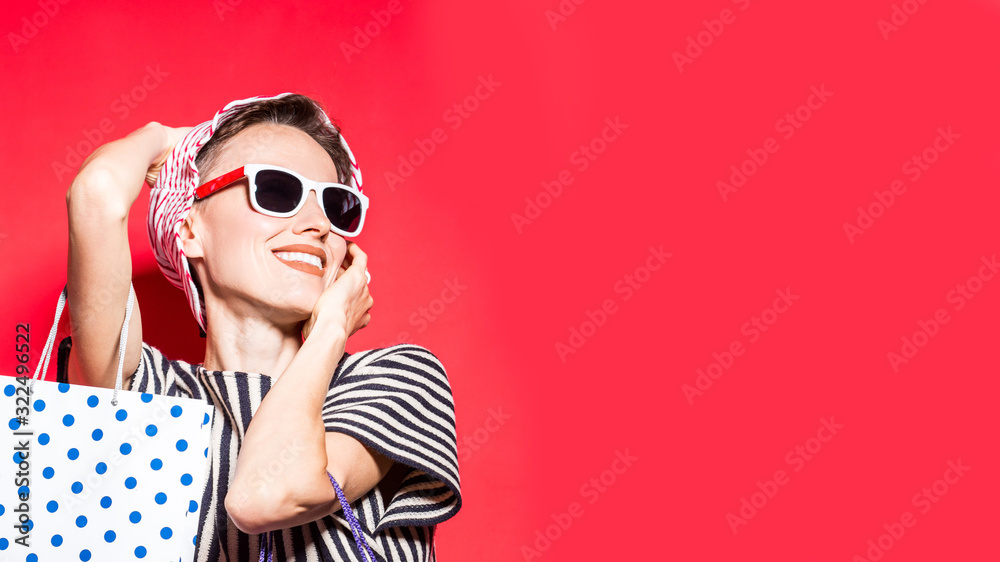 Happy shopping woman with shopping bags over bright red background wearing striped clothes hat and shirt