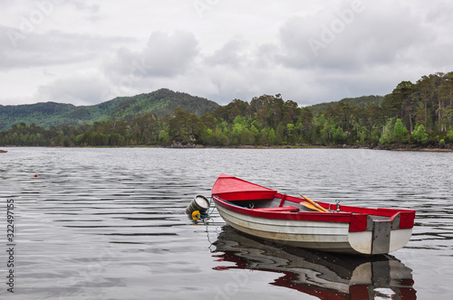 A small red boat by the side of a lake in the Glen Affric, Highlands, Scotland, picture evoking peace and tranquility photo