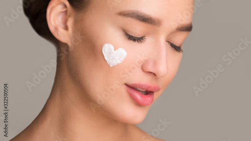 Beauty skin care. Girl with moisturizer cream in hearth shape photo