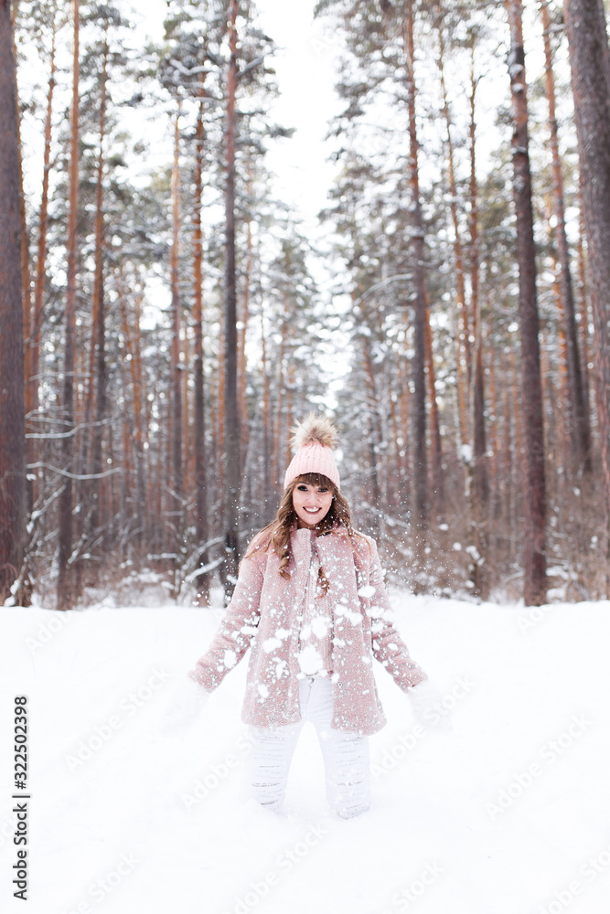 A beautiful pretty young girl with curly hair and a snow-white smile in a pink fur coat is walking and fooling around in the winter forest against the background of snow and trees, enjoy A beautiful pretty young girl with curly hair and a snow-white smile in a pink fur coat is walking and fooling around in the winter forest against the background of snow and trees, enjoy