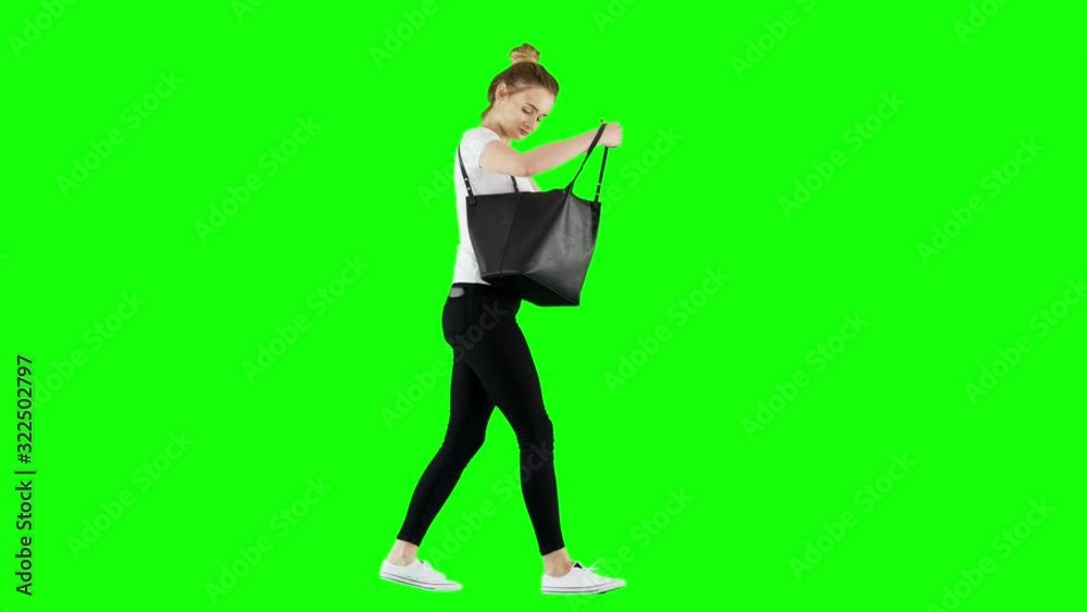 Young Girl Trying to Find Something in Her Purse While Walking on Green Screen Young Girl Trying to Find Something in Her Purse While Walking on Green Screen