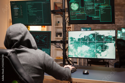 Cyber criminal wearing a hoodie writing a dangerous virus photo
