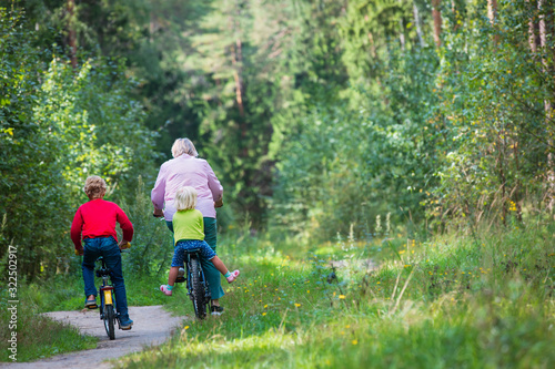 active grandmother with kids riding bikes in nature