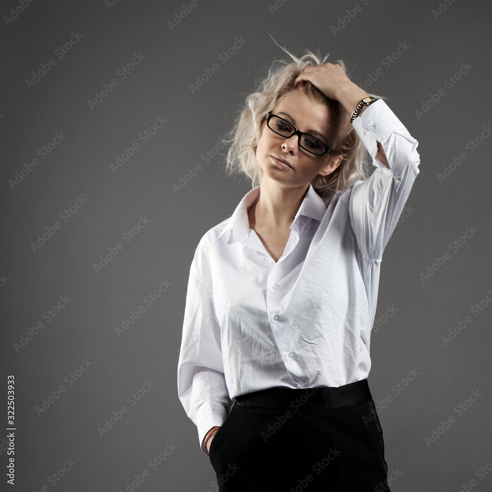 Portrait of an young beautiful blonde caucasian girl in a white shirt and a black pants holds his head in thought Portrait of an young beautiful blonde caucasian girl in a white shirt and a black pants holds his head in thought