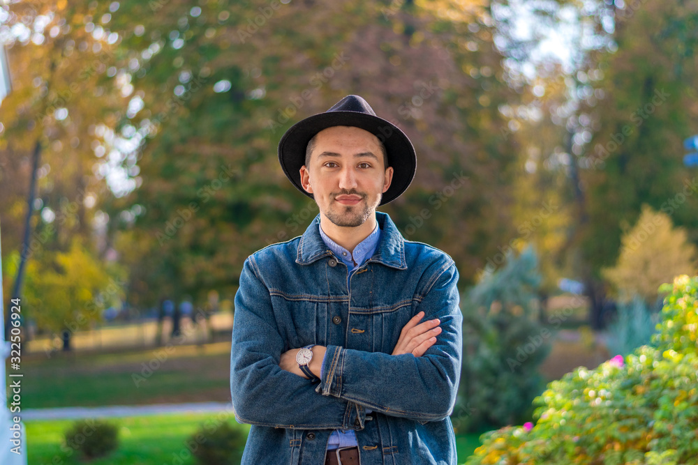 Handsome young man looking at the camera. Portrait of a confident and successful young man with a denim jacket and blue shirt outside. Happy guy smiling