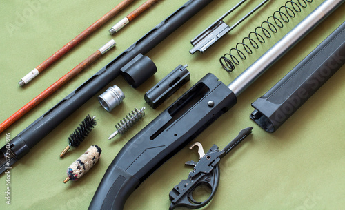 black disassembled shotgun and cleaning kit on the green background