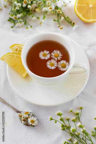 Delicate Provencal style still life with herbal tea and flowers. Hot tea with chamomile and lemon for the treatment or prevention of colds or flu using the folk method. Light, romantic photo.