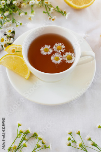 Provencal style still life with herbal tea and flowers. Hot tea with chamomile and lemon for the treatment or prevention of colds or flu using the folk method. Light romantic photo.