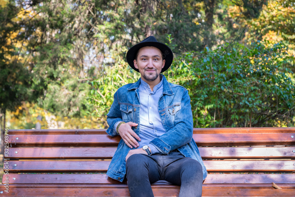 Handsome young man looking at the camera. Portrait of a confident and successful young man with a denim jacket and blue shirt outside. Happy guy smiling