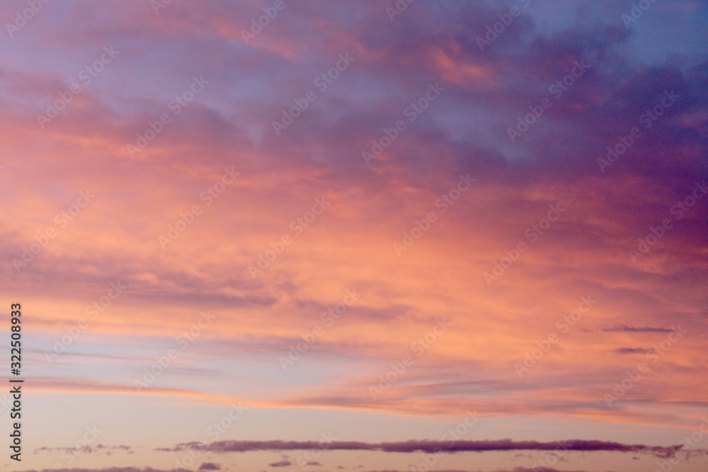 Dreamy evening sky  in pastel tones with fluffy pink orange clouds at sunset