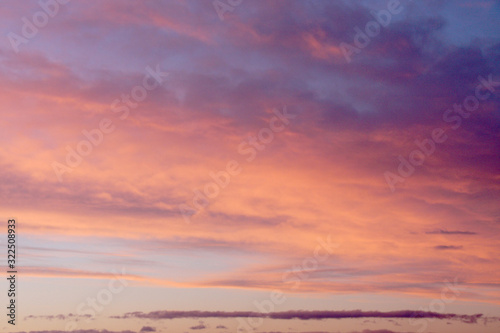 Dreamy evening sky in pastel tones with fluffy pink orange clouds at sunset