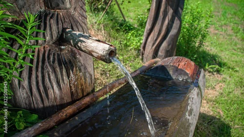 Water running out of a selfmade water tap. Slowmotion. Sunny day. Prevalje, Slovenia photo