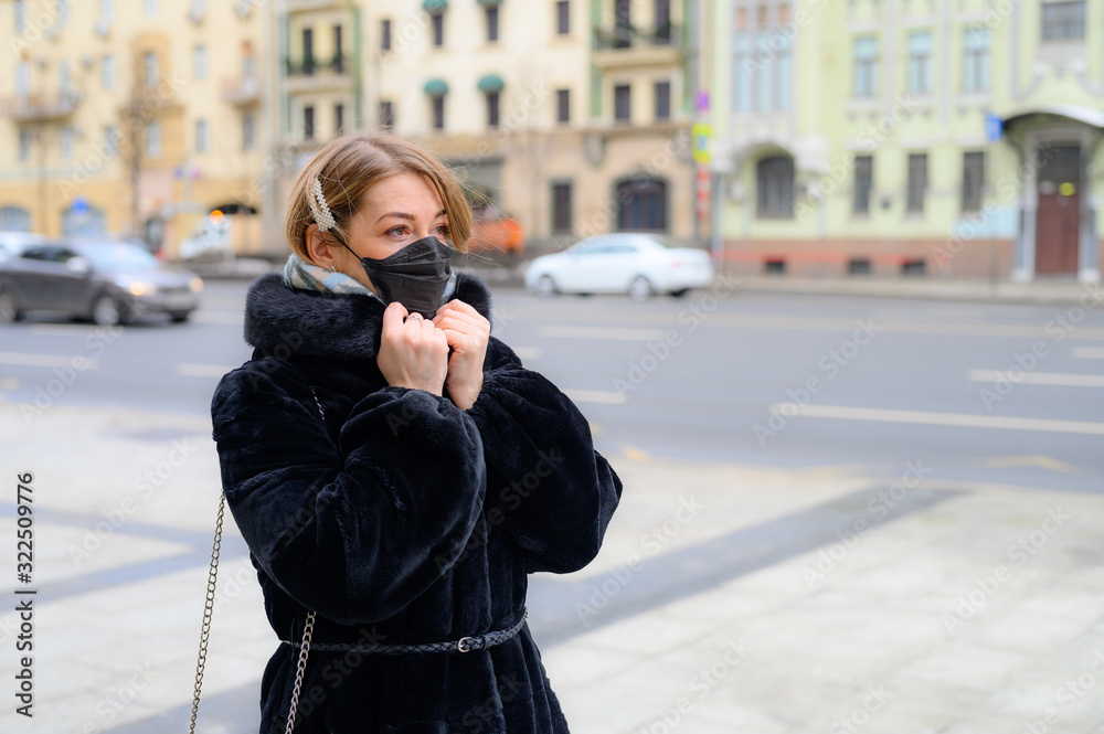 young european woman in protective disposable medical black mask in city outdoor. concept protection of dangerous 2019-nCoV influenza coronavirus, mutated and spreading in China