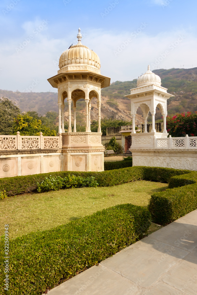 Gatore Ki Chhatriyan landmark tourism spot in Jaipur India ancient architecture of ivory and white marble sandstone pavilions canopy dome Europe design style with green grass garden and mountain hills