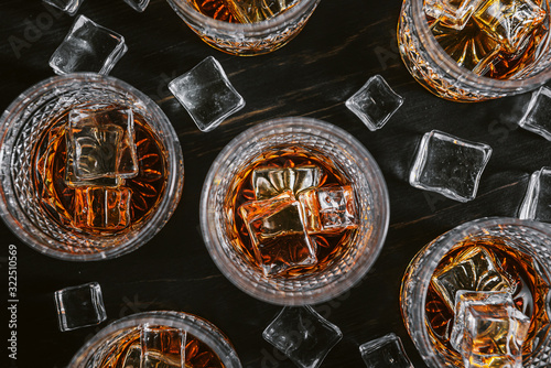 Canvas Print many glasses of whiskey with ice on a black table