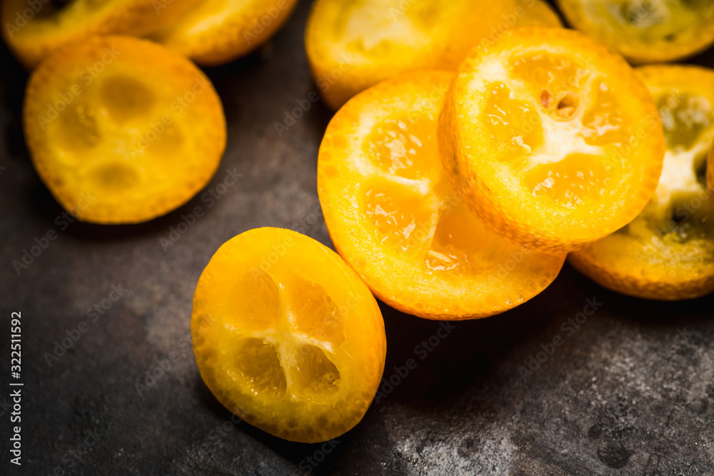 Sliced ripe kumquats on the rustic wooden background. Selective focus. Shallow depth of field.