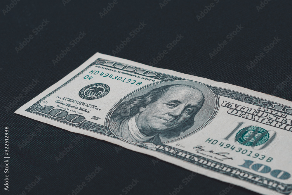 One hundred american dollars lie on a black background, free space for inscription. One hundred american dollars lie on a black background, free space for inscription.