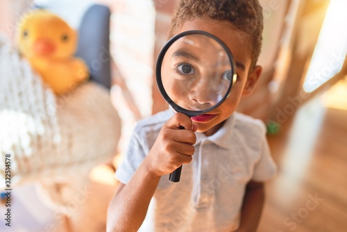 Beautiful african american toddler playing with loupe at kindergarten photo