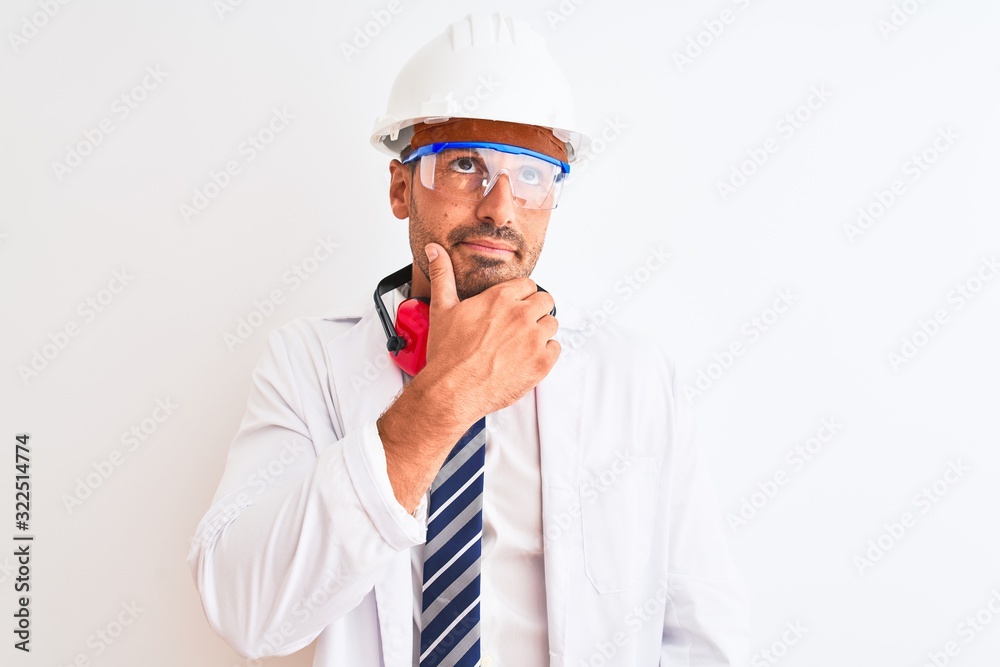 Young chemist man wearing security helmet and headphones over isolated background with hand on chin thinking about question, pensive expression. Smiling with thoughtful face. Doubt concept.