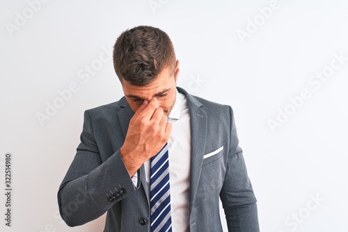 Young handsome business man wearing suit and tie over isolated background tired rubbing nose and eyes feeling fatigue and headache. Stress and frustration concept.