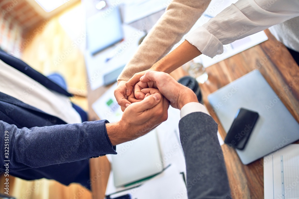 Group of business workers standing with hands together doing symbol at the office Group of business workers standing with hands together doing symbol at the office