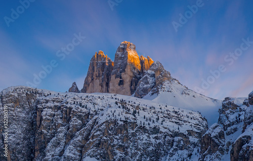 Colorful sunset sunset in Dolomites mountains, three peaks of Tre Cime di Lavaredo in snowy and cloudy background. Italy, Europe. January 2020
