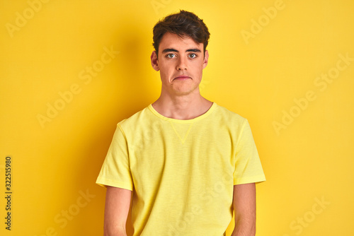 Teenager boy wearing yellow t-shirt over isolated background depressed and worry for distress, crying angry and afraid. Sad expression.