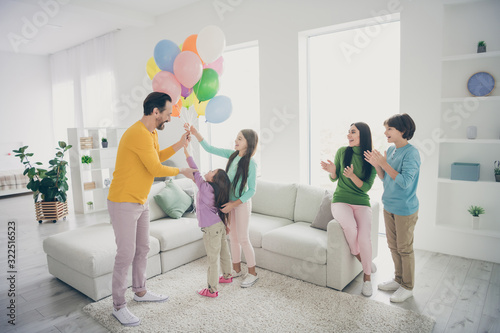 Full length photo positive fun people dad daddy mom mommy prepare air baloons woman family day celebration three preteen small kids clap hands ovation sit comfort couch house