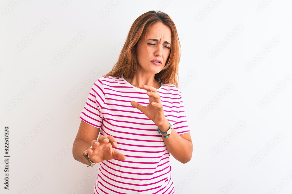 Young redhead woman wearing striped casual t-shirt stading over white isolated background disgusted expression, displeased and fearful doing disgust face because aversion reaction. With hands raised Young redhead woman wearing striped casual t-shirt stading over white isolated background disgusted expression, displeased and fearful doing disgust face because aversion reaction. With hands raised