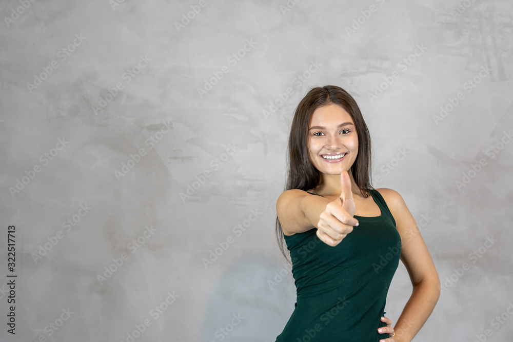 Young pretty woman happy smiling face giving thumbs up on grey background. copy space Young pretty woman happy smiling face giving thumbs up on grey background. copy space