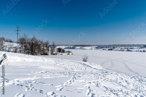 Spacious snow landscape. River and hills in Russia, white winter on the terrain, a lot of fluffy snow and ice under a beautiful blue sky. Rostov region, town of Shakhty, the river Grushevka