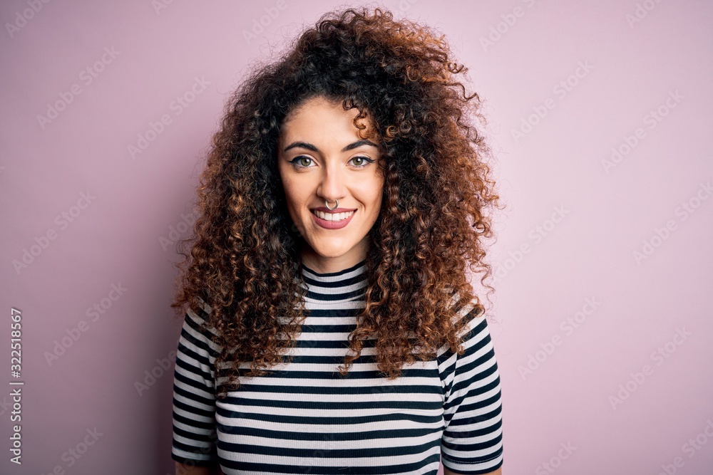 Young beautiful woman with curly hair and piercing wearing casual striped t-shirt with a happy and cool smile on face. Lucky person. Young beautiful woman with curly hair and piercing wearing casual striped t-shirt with a happy and cool smile on face. Lucky person.