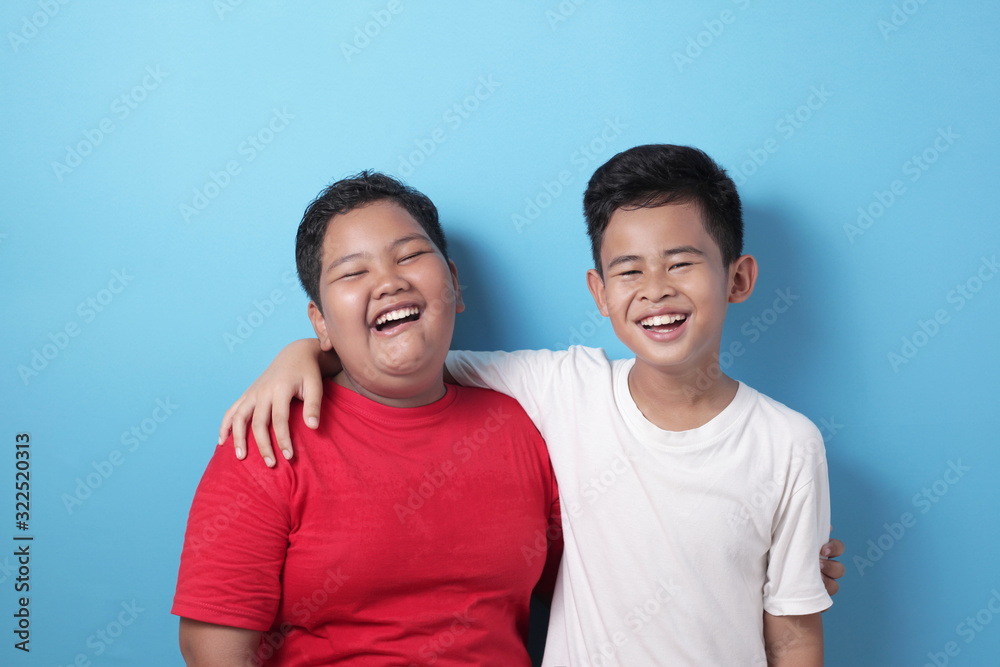 Two Asian boys looking at camera, smiling and laughing, best friends happiness Two Asian boys looking at camera, smiling and laughing, best friends happiness