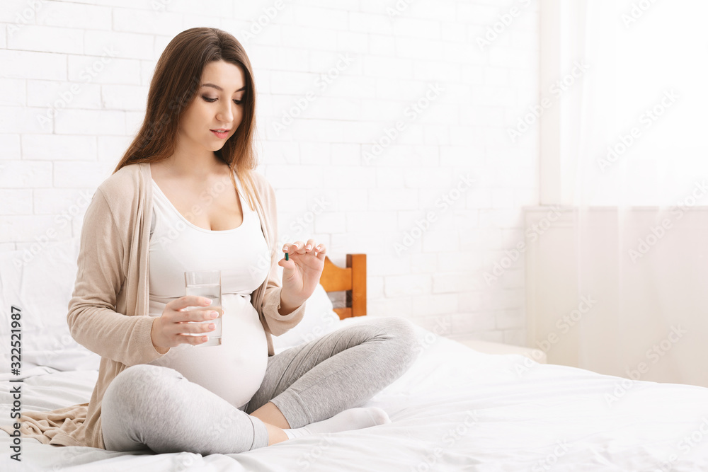 Expectant lady taking bunch of pills and glass of water Expectant lady taking bunch of pills and glass of water
