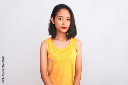 Young chinese woman wearing yellow casual t-shirt standing over isolated white background Relaxed with serious expression on face. Simple and natural looking at the camera.