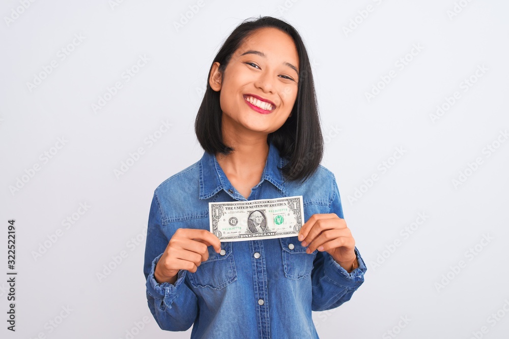 Young beautiful chinese woman holding one dollar standing over isolated white background with a happy face standing and smiling with a confident smile showing teeth Young beautiful chinese woman holding one dollar standing over isolated white background with a happy face standing and smiling with a confident smile showing teeth