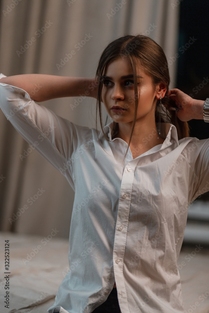 Cute young model of a beautiful woman with brown hair in a fashionable  classic white shirt