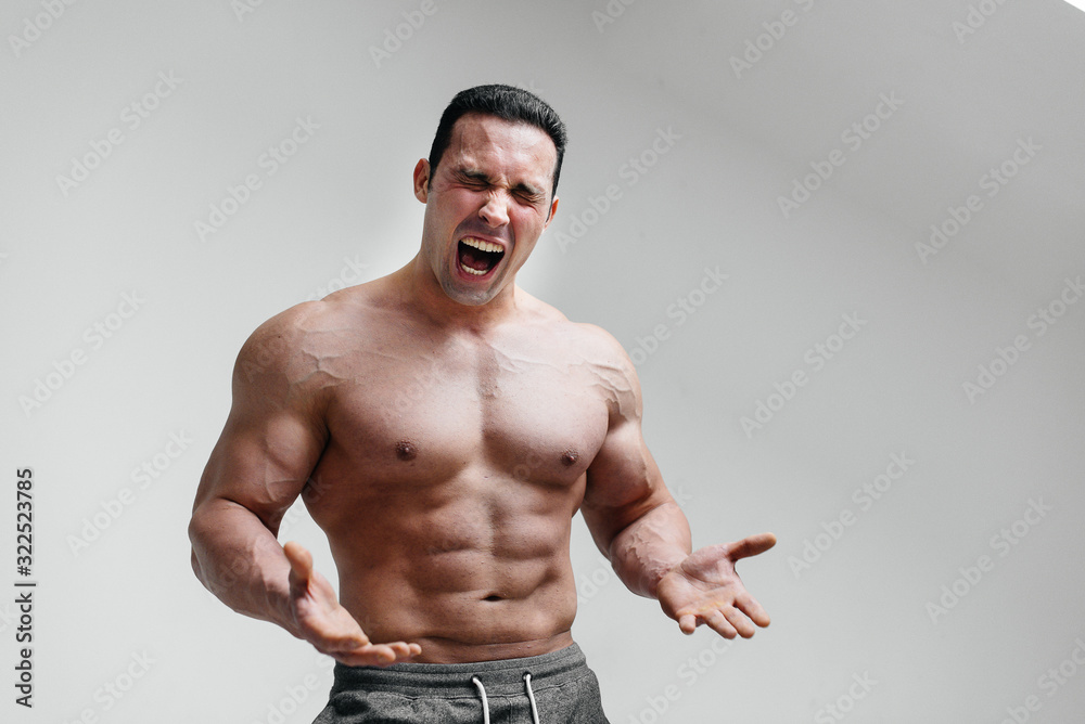 A sporty guy screams in rage against a white background. Anger. Threat A sporty guy screams in rage against a white background. Anger. Threat