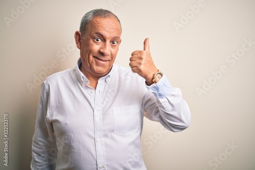 Senior handsome businessman wearing elegant shirt standing over isolated pink background doing happy thumbs up gesture with hand. Approving expression looking at the camera showing success.