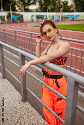 Stylish female athlete leaning on stadium railing