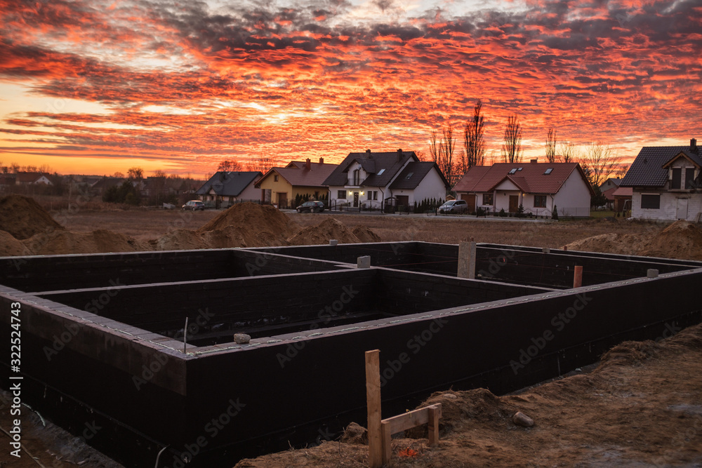 Building a house with a beautiful sky during sunset and other houses in the background