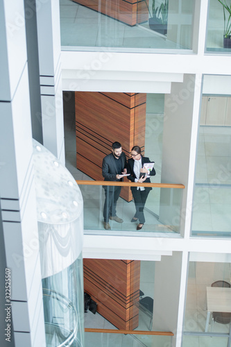 Above view of modern young business specialists in black outfits standing on balcony and discussing strategy of development