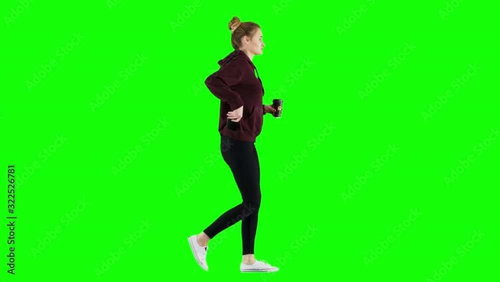 Female in a Hoodie Checks Her Smartphone While Walking with Coffee Green Screen Female in a Hoodie Checks Her Smartphone While Walking with Coffee Green Screen
