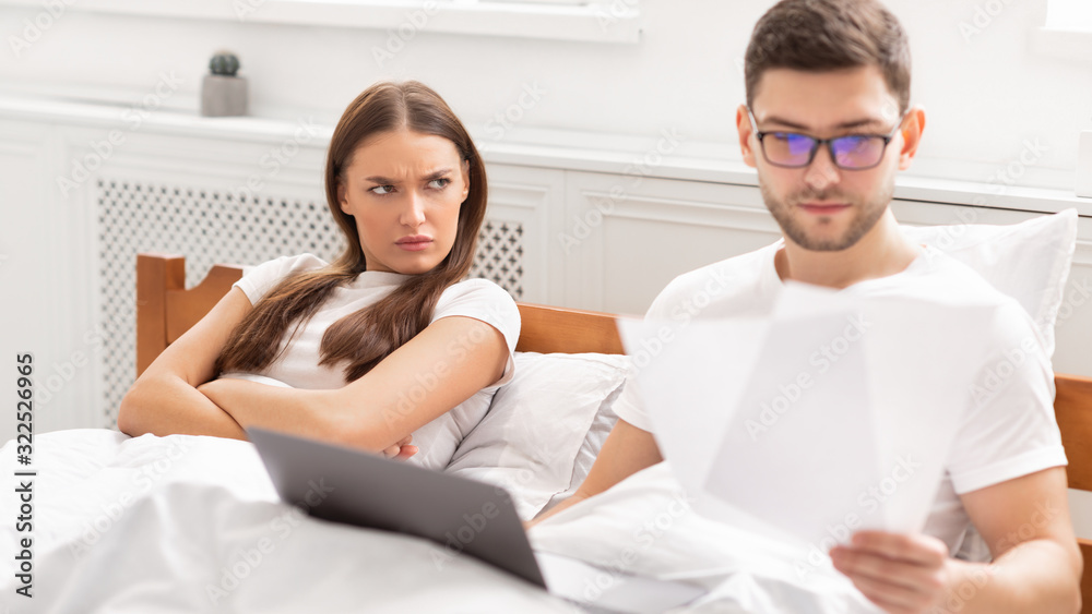 Busy Freelancer Working Lying With Angry Girlfriend In Bed, Panorama Busy Freelancer Working Lying With Angry Girlfriend In Bed, Panorama