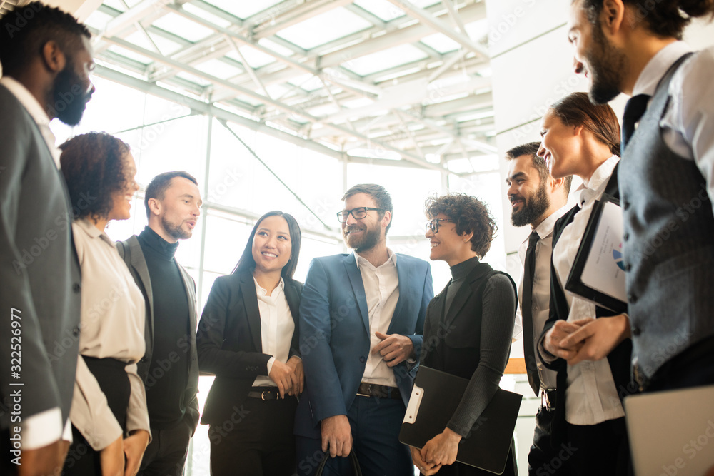 Group of creative young multi-ethnic business colleagues standing in circle and brainstorming about new campaign Group of creative young multi-ethnic business colleagues standing in circle and brainstorming about new campaign